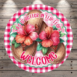 A circular sign with a red and white checkered border, featuring a pair of flip-flops with pink and red flowers on the sides, and the text "Life is better in flip flops" and "Welcome" written around the edges.