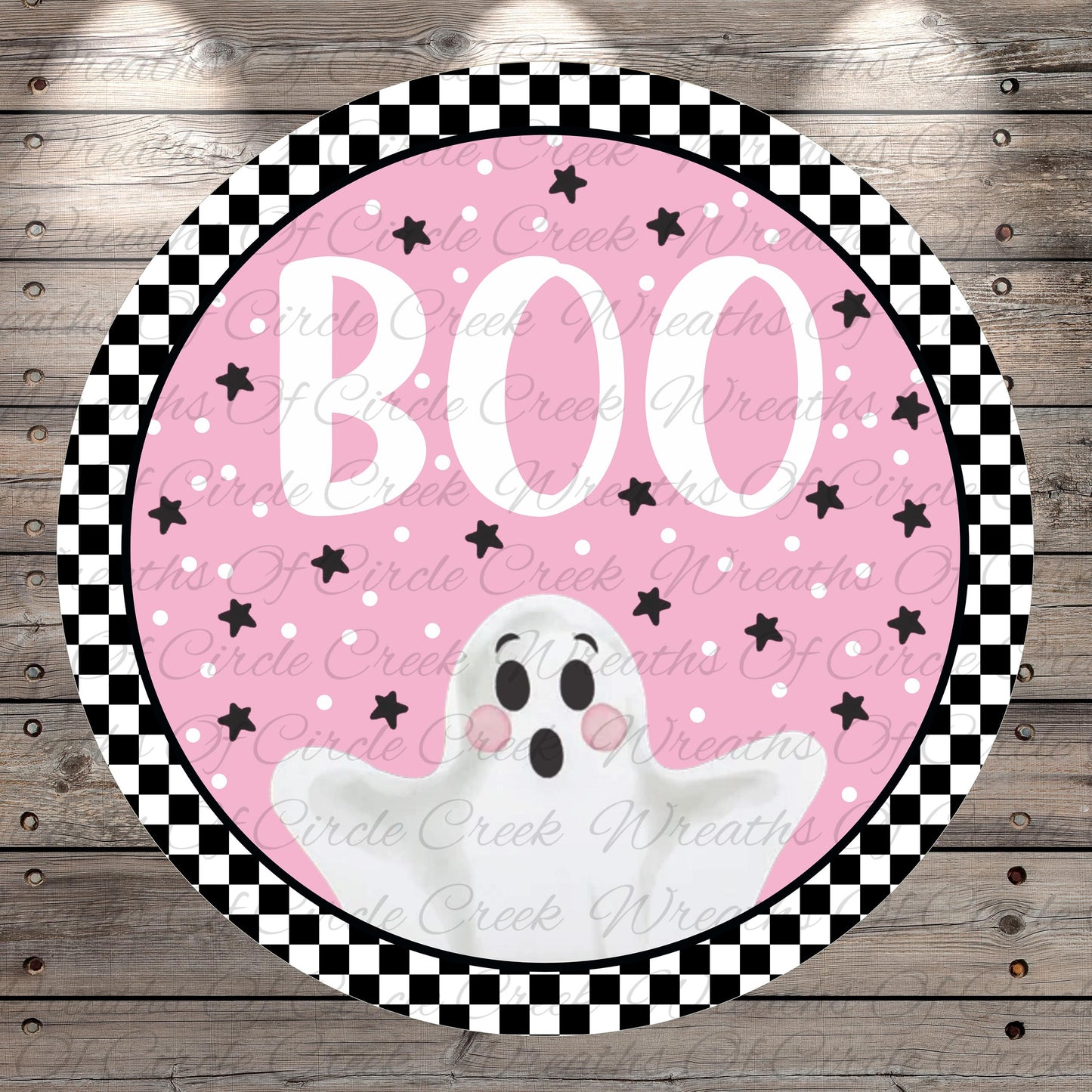 A circular Halloween-themed decoration with a pink background, black and white checkered border, and a white ghost with a black face and arms.