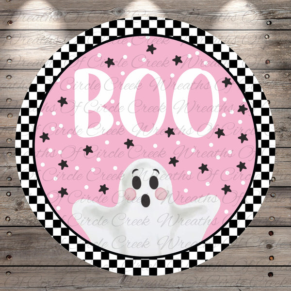 A circular Halloween-themed decoration with a pink background, black and white checkered border, and a white ghost with a black face and arms.