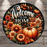 A circular sign with a black background featuring a vibrant autumnal design with flowers, pumpkins, and leaves. The text "Welcome to our Home" is prominently displayed in the center of the sign.