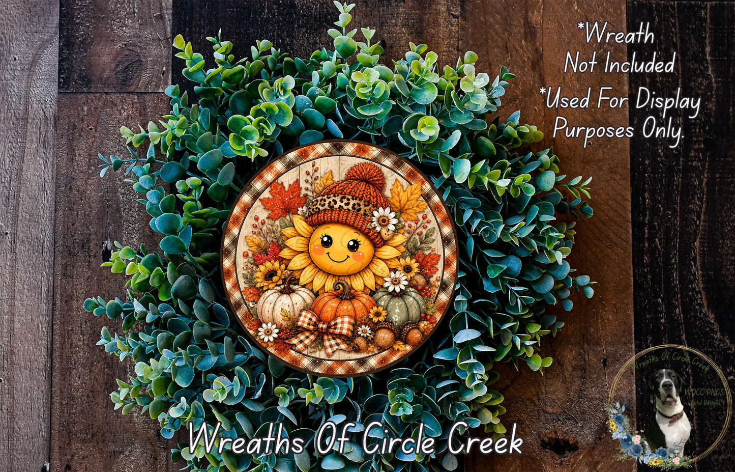 A wreath made of various fall-themed elements, including a sunflower, pumpkins, and pine cones, is displayed on a wooden surface.
