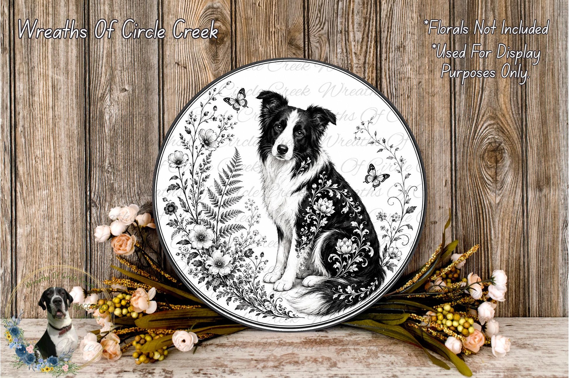 A decorative plate featuring a black and white illustration of a dog surrounded by floral elements, placed on a wooden surface with a wreath of flowers and greenery.