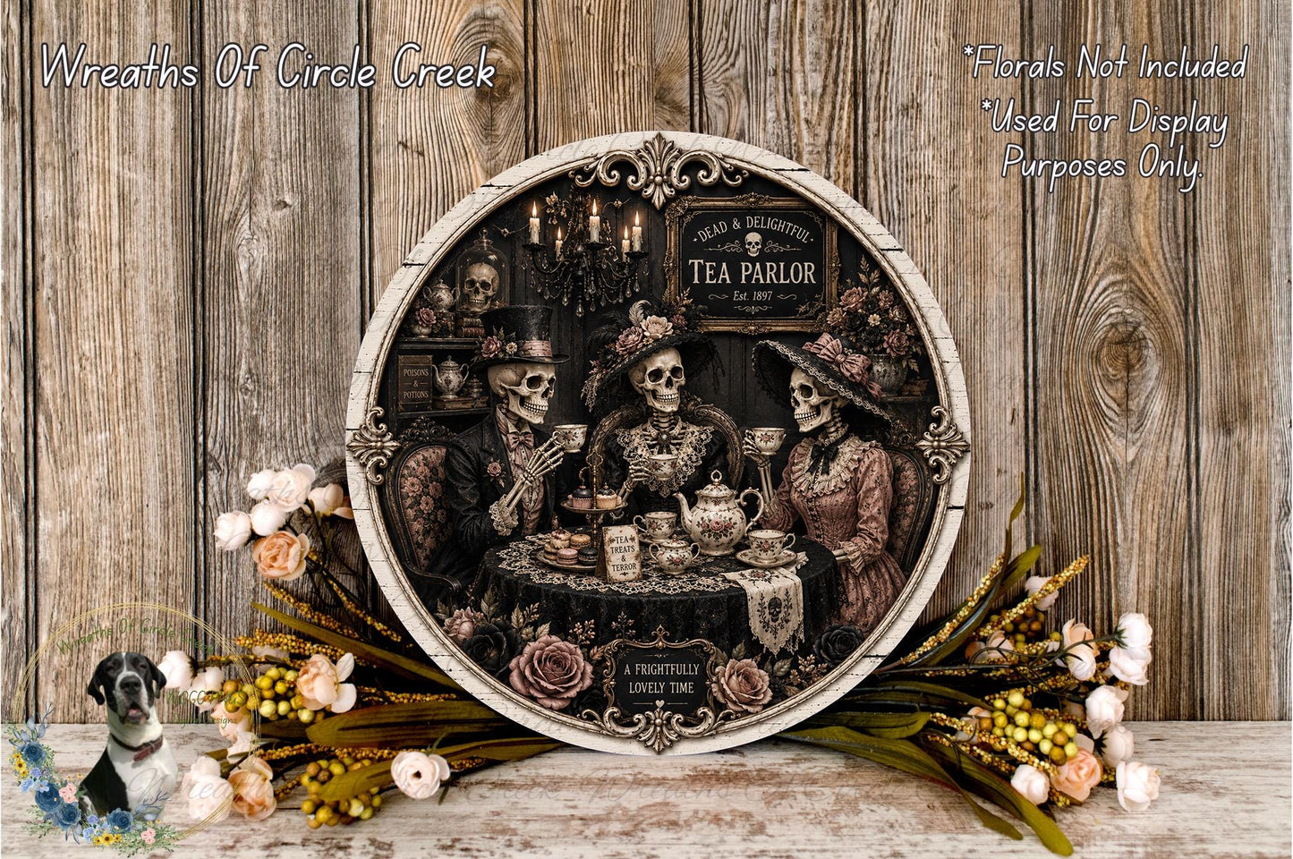 The image is a decorative wall hanging featuring three skeletal figures dressed in Victorian-era clothing, sitting at a table and enjoying tea. The wall hanging is surrounded by floral arrangements and placed on a wooden surface.