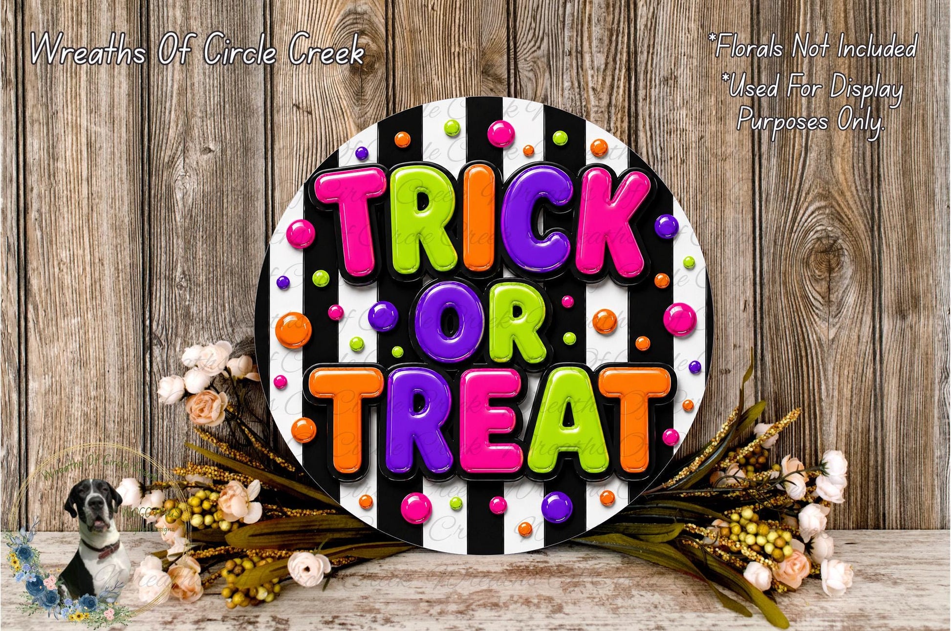 a colorful and festive Halloween decoration with the text "TRICK OR TREAT" displayed prominently. The decoration is surrounded by a floral arrangement and is set against a rustic wooden background.