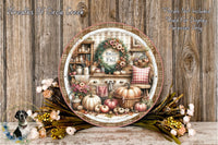 a decorative plate with a wreath and fall-themed items, such as pumpkins, flowers, and a kitchen scene, displayed on a wooden surface.