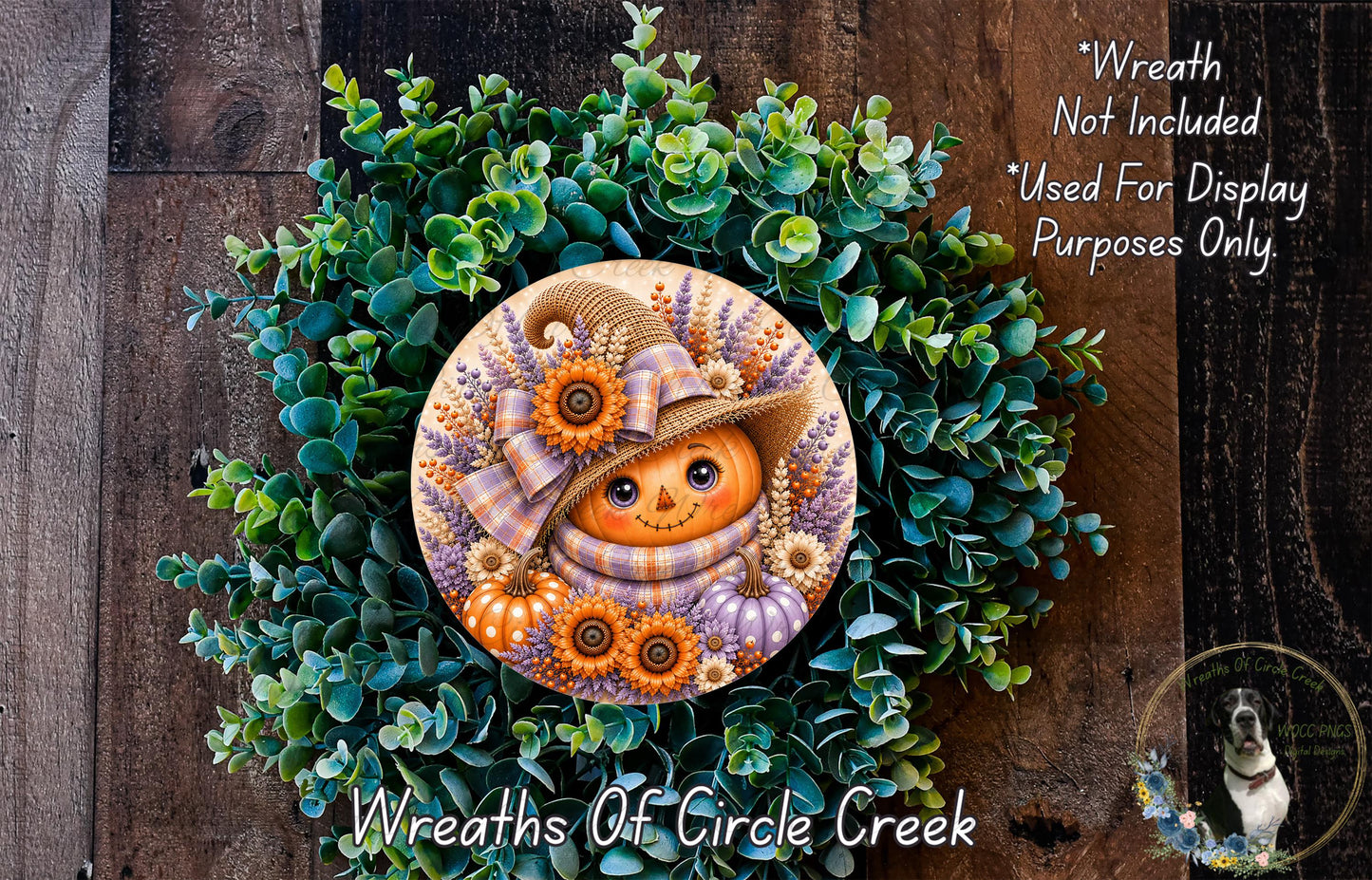 a wreath with a pumpkin face and a witch hat, surrounded by green foliage.
