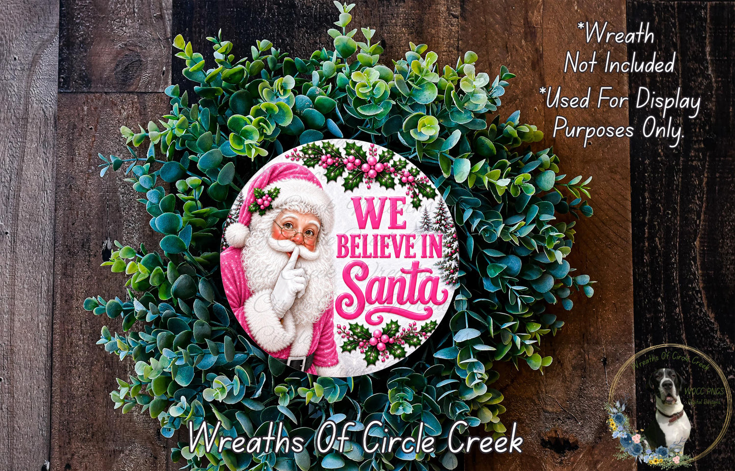 A wreath made of green leaves and flowers, featuring a Santa Claus image and the text "We Believe in Santa" in pink and white.