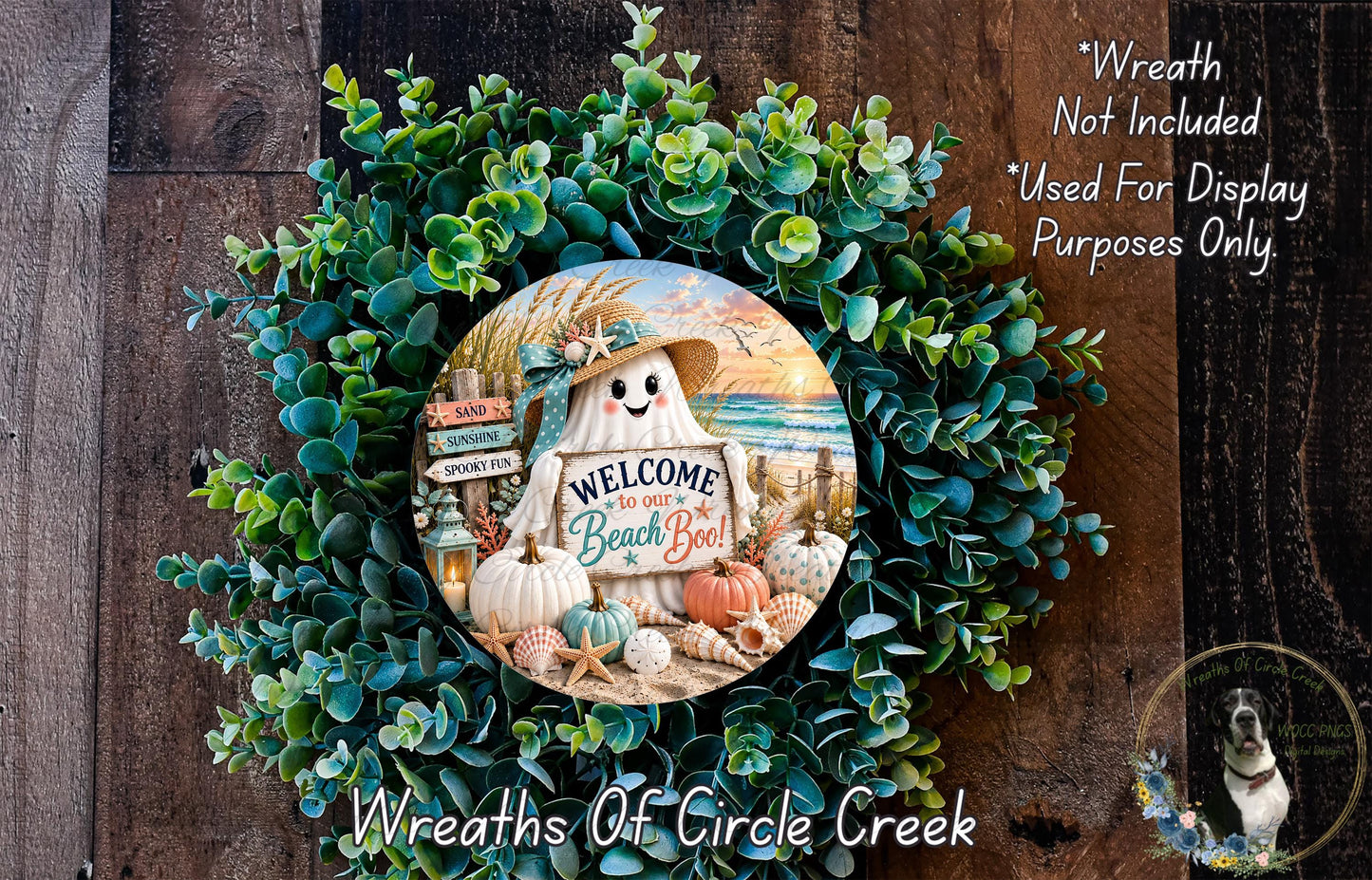 a wreath with a sign that says "Welcome to our Beach Bowl!" The wreath is made of green foliage and has a small ghost figure in the center. The sign is surrounded by various beach-themed items such as pumpkins, seashells, and a starfish. The wreath is displayed on a wooden surface, and there is a small dog in the bottom right corner of the image.