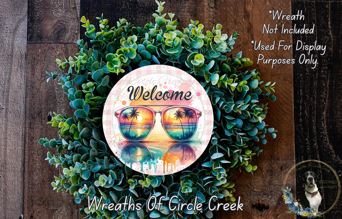 A wreath made of green leaves and a pair of sunglasses with a sunset reflection, placed on a wooden surface.
