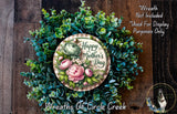 A wreath made of various green plants and flowers, with a circular sign that reads "Happy Mother's Day" in the center.