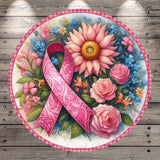A pink ribbon, a symbol of breast cancer awareness, is surrounded by a vibrant floral arrangement of pink roses, blue forget-me-nots, and other colorful flowers on a wooden background.