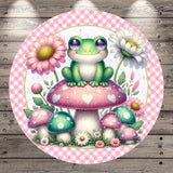 A whimsical illustration of a green frog sitting on a pink mushroom, surrounded by colorful flowers and mushrooms, all set against a pink and white checkered background.