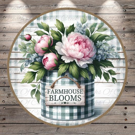 A round wooden sign with the text "FARMHOUSE BLOOMS" is displayed in front of a vase filled with pink peonies and green leaves.