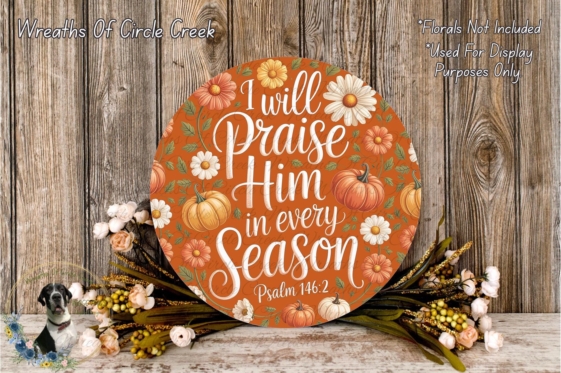 a circular sign with a floral design and text, surrounded by a wreath of flowers and greenery.