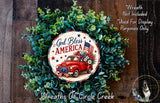 A wreath made of green leaves and a red truck with an American flag, featuring the text "God Bless America" and "Wreaths of Circle Creek".