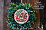 a wreath made of green leaves and flowers, with a red wagon and a basket of flowers on top of it. The wreath is displayed on a wooden surface, and there is a text overlay that reads "Wreath Not Included * Used For Display Purposes Only".