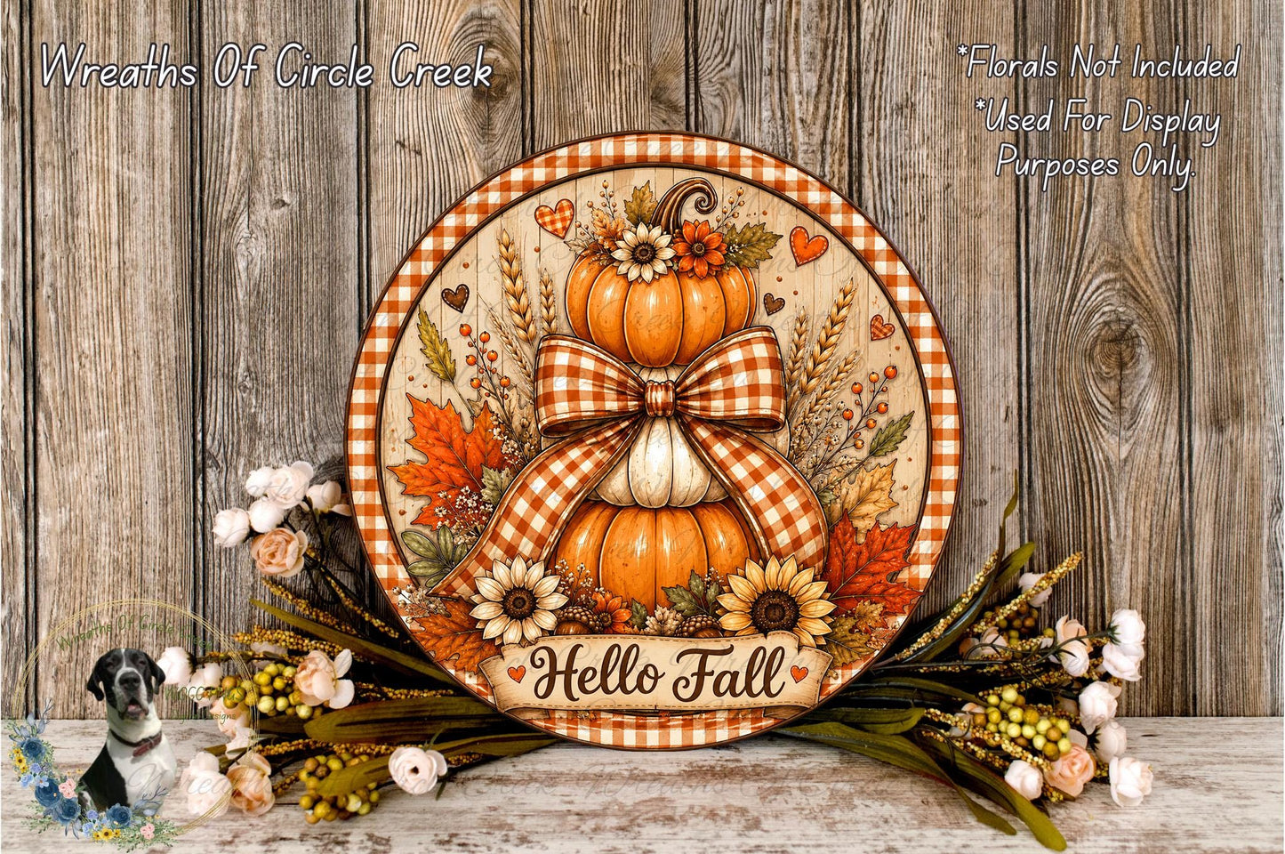 A decorative round wreath with a bow, featuring autumn-themed elements such as pumpkins, sunflowers, and leaves, placed on a wooden surface.