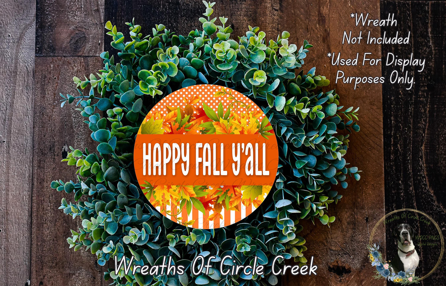 a wreath made of green leaves and flowers, with a large orange circular sign in the center that says "HAPPY FALL Y'ALL". The wreath is displayed on a wooden surface, and there is a small dog in the bottom right corner of the image.