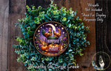 a wreath made of various greenery and a decorative metal plate with a farmhouse-themed design.