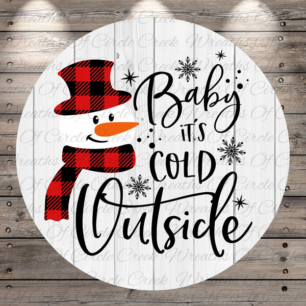 A snowman wearing a red and black plaid hat and scarf, with the text "Baby, it's cold outside" written around it.