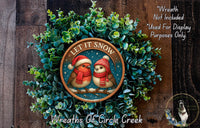 A wreath made of green plants with two birds wearing red and white hats, and the text "LET IT SNOW" on the wreath.