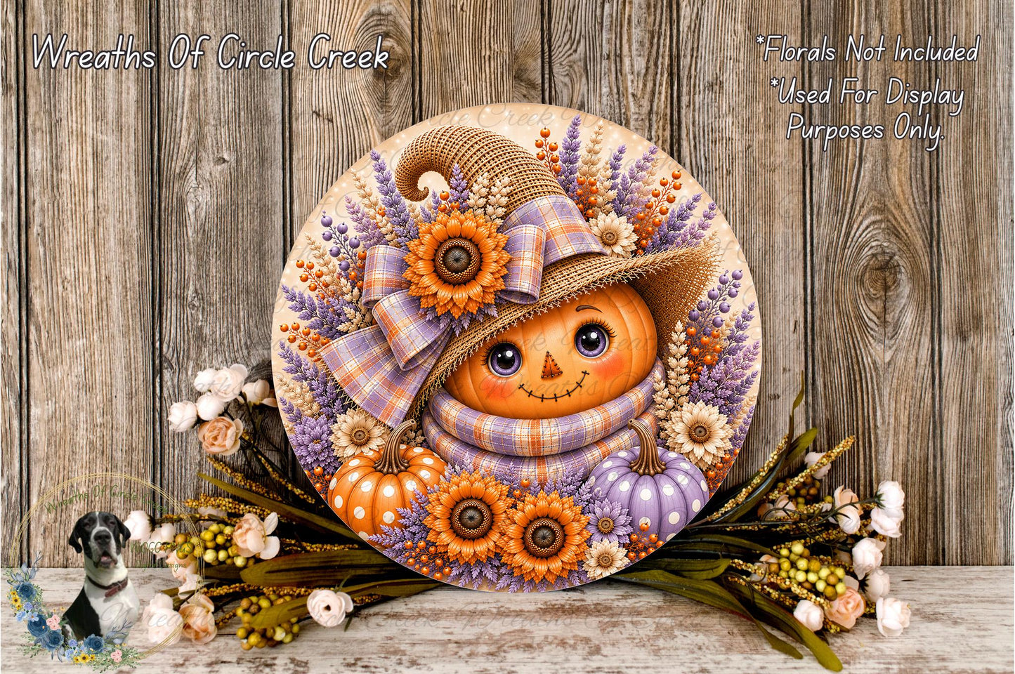 A decorative wreath featuring a pumpkin face, flowers, and a plaid hat, placed on a wooden surface.