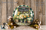 a decorative plate with a floral design, surrounded by flowers and greenery, placed on a wooden surface.