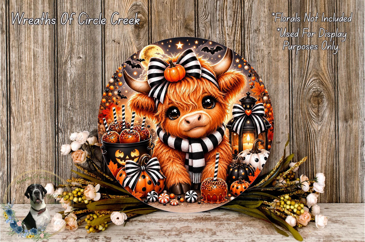 A decorative wreath featuring a cartoon cow surrounded by Halloween-themed elements, including pumpkins, lanterns, and flowers, against a wooden background.