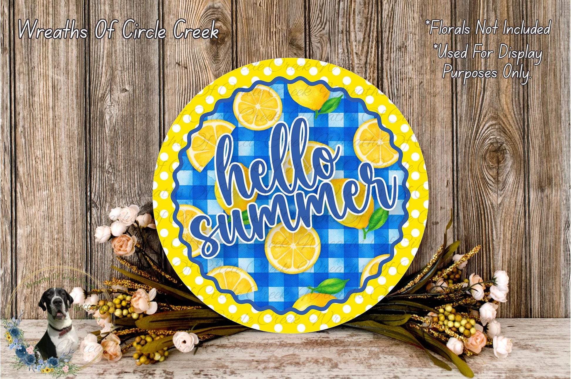a round sign with the text "Hello Summer" on it, surrounded by flowers and placed on a wooden surface.