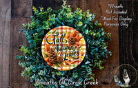 a wreath made of various fall-themed elements, including pine cones, leaves, and flowers, displayed on a wooden surface.