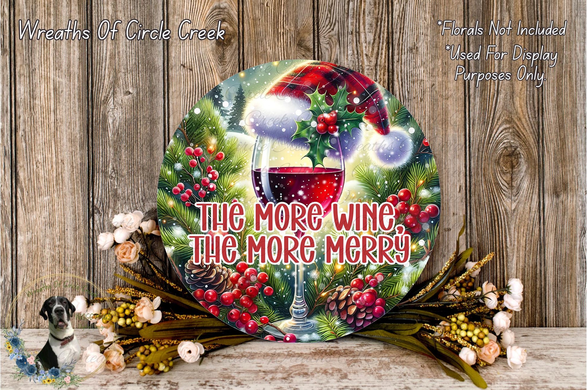A festive wreath with a wine glass and a Santa hat, surrounded by holiday decorations such as pine cones, berries, and flowers, against a wooden background.