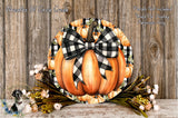 a decorative pumpkin wreath with a black and white checkered bow, placed on a wooden surface. The wreath is surrounded by a variety of fall-themed flowers, creating a festive and seasonal display.